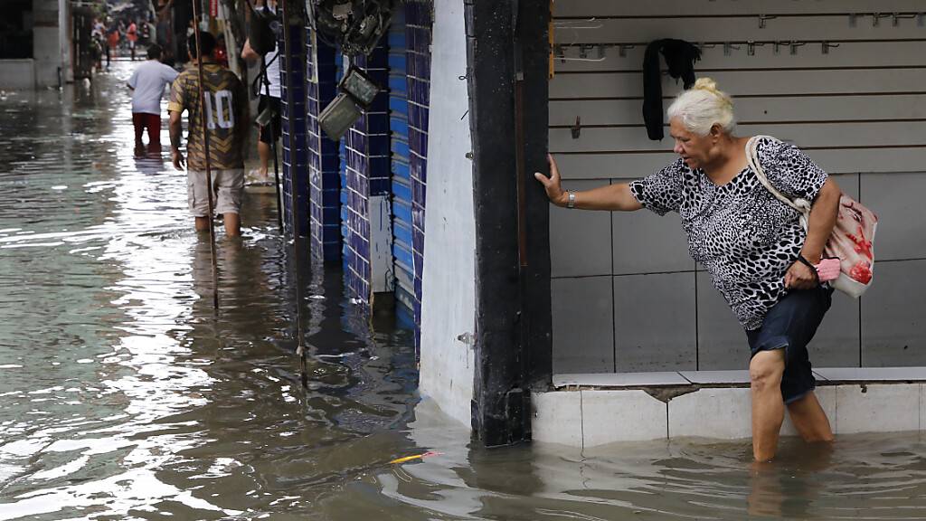 ARCHIV - Eine ältere Frau versucht sich den Weg über eine überschwemmte Straße zu bahnen. Nach den Erdrutschen und Überschwemmungen in Folge von heftigem Regen in Brasilien ist die Zahl der Toten auf mindestens 20 gestiegen, teilte das Nachrichtenportal G1 am Dienstag mit. Foto: Fernando Fraz/Agencia Brazil/dpa - ACHTUNG: Nur zur redaktionellen Verwendung und nur mit vollständiger Nennung des vorstehenden Credits