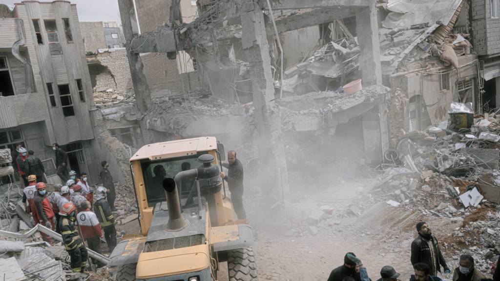 Ersthelfer benutzen einen Bagger, um die Trümmer zu beseitigen und nach Opfern in einem Wohnhaus zu suchen, das bei einem nächtlichen Angriff während der amerikanisch-israelischen Militäraktion getroffen wurde. Foto: Mati Hashemi/AP/dpa