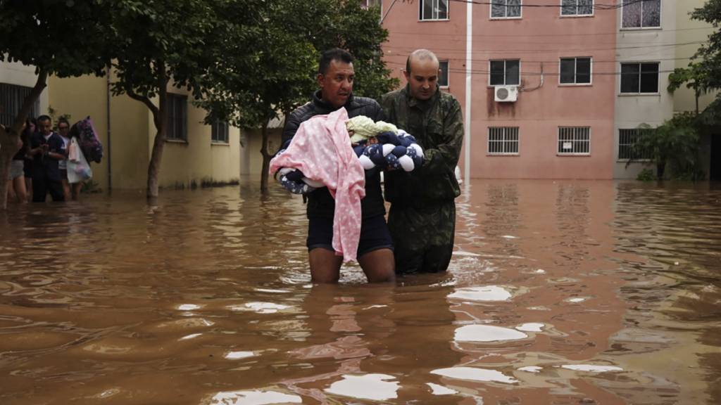 dpatopbilder - Männer waten durch eine überschwemmte Straße im brasilianischen Canoas. Foto: Carlos Macedo/AP