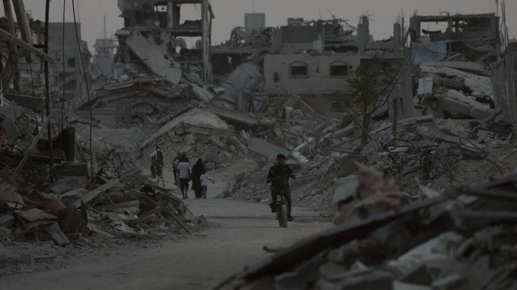 ARCHIV - Vertriebene Palästinenser gehen zwischen den Ruinen zerstörter Gebäude in Chan Junis im Gazastreifen. Foto: Abdel Kareem Hana/AP/dpa