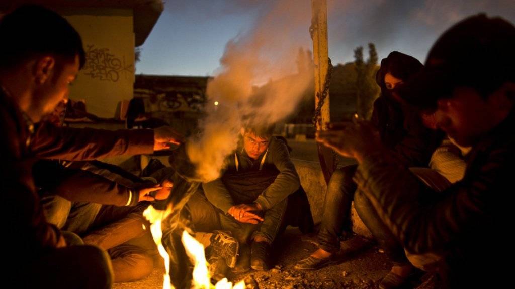 Afghanische Flüchtlinge wärmen sich auf Lesbos an einem Feuer. Auf der griechischen Insel soll in den kommenden Tagen der erste Hotspot für die Registrierung von Flüchtlingen seinen Betrieb aufnehmen (Archiv)