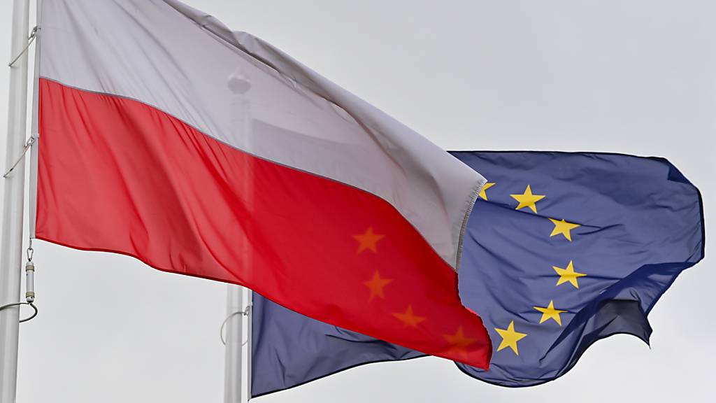 ARCHIV - Die weiß-rote Nationalfahne Polens und dahinter die Fahne der Europäischen Union (EU) wehen im Wind. Foto: Patrick Pleul/dpa-Zentralbild/ZB