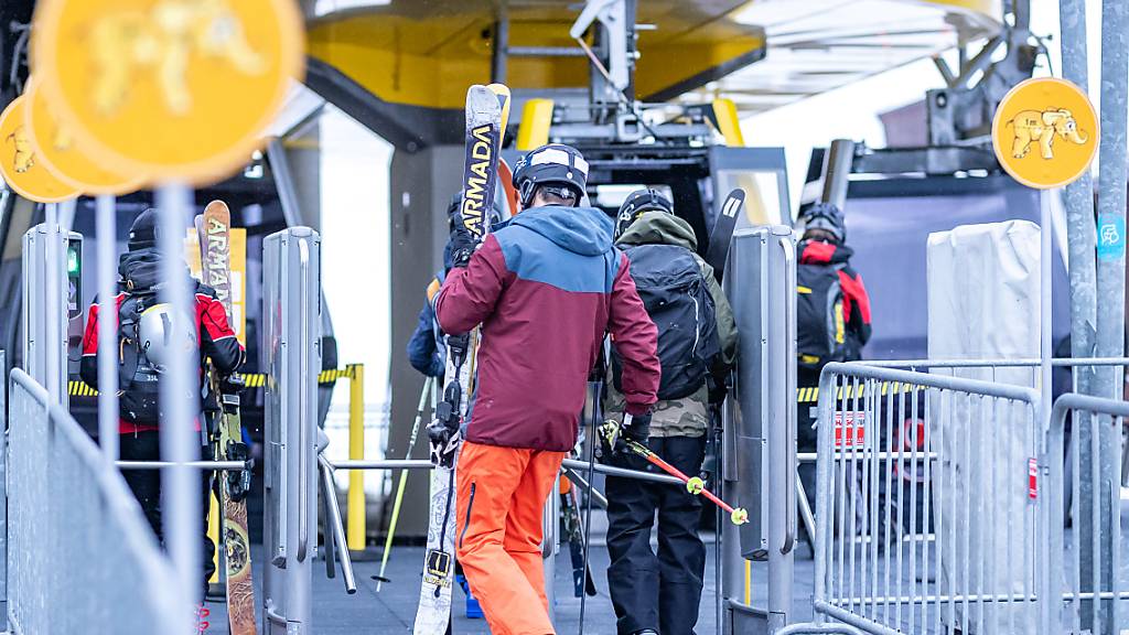 Menschen gehen mit ihren Skiern zu einer Gondel in der Talstation des Skigebiets Zillertal Arena. Foto: Expa/Johann Groder/APA/dpa