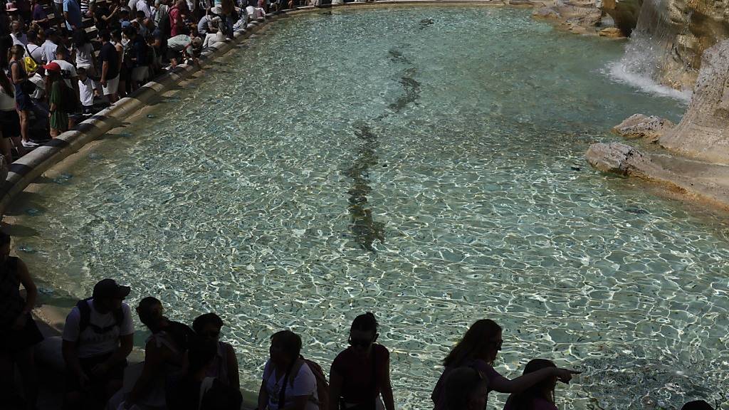 ARCHIV - Touristen kühlen sich am Trevi-Brunnen ab. Foto: Gregorio Borgia/AP/dpa