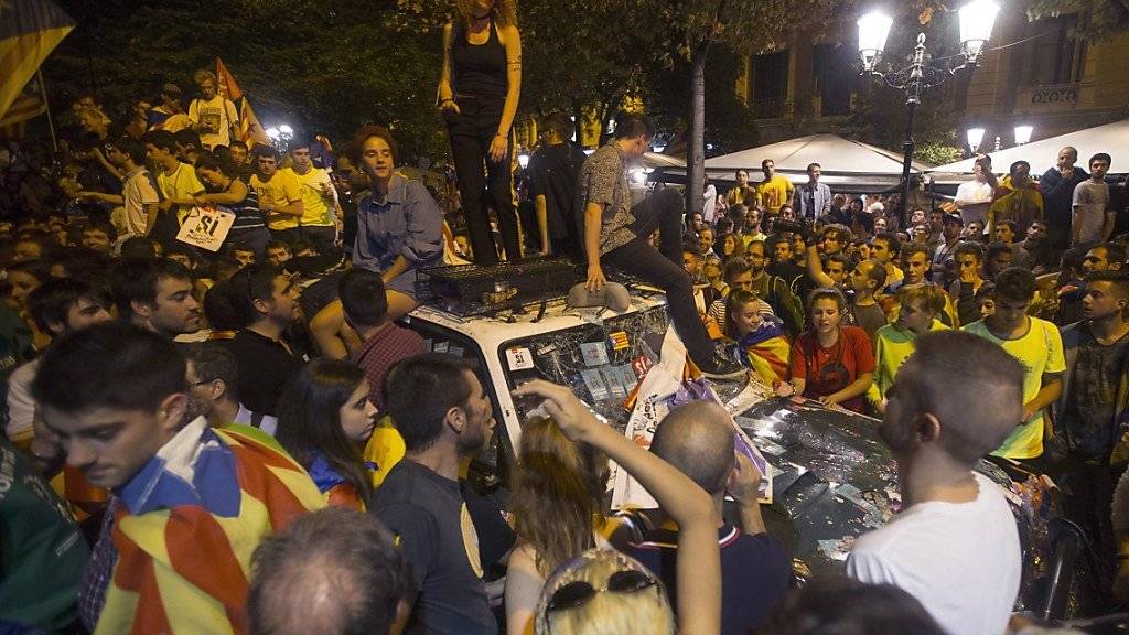 Demonstranten in Barcelona belagern ein Auto der spanischen Bundespolizei.