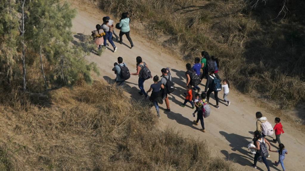 ARCHIV - Migranten gehen einen Feldweg entlang, nachdem sie die Grenze zwischen den USA und Mexiko überquert haben. Die mexikanisch-amerikanische Grenze war im vergangenen Jahr laut einer UN-Analyse die gefährlichste Migrationsroute weltweit über Land. Foto: Julio Cortez/AP/dpa