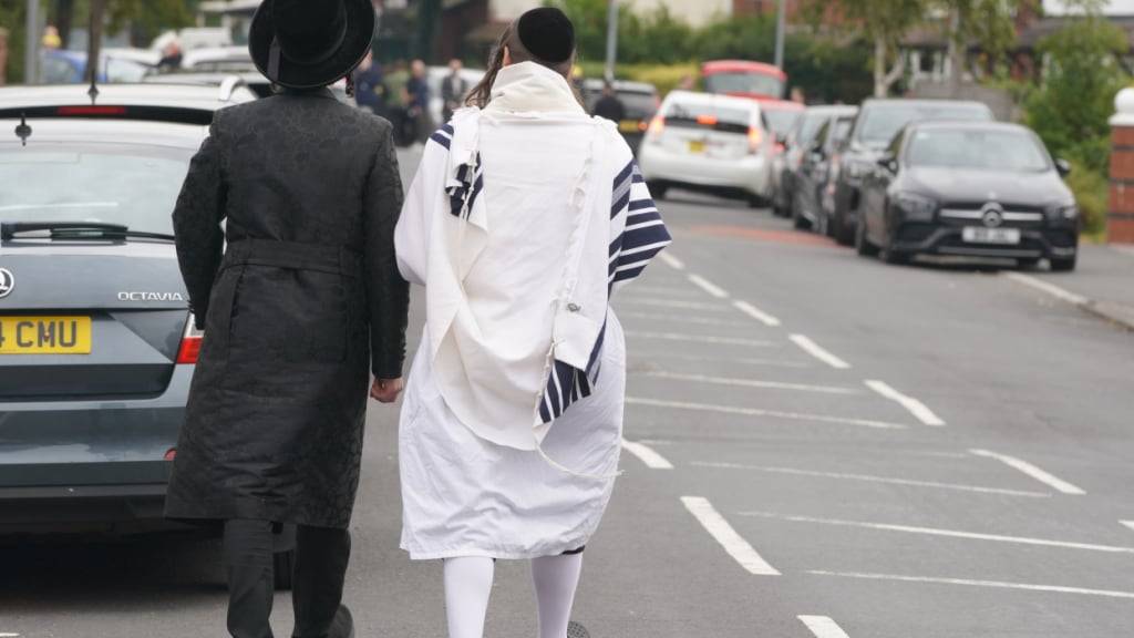 Orthodoxe jüdische Männer gehen in der Nähe der Synagoge der Heaton Park Hebrew Congregation in Crumpsall. Der Angriff auf Menschen vor einer Synagoge in Manchester mit zwei Todesopfern am höchsten jüdischen Feiertag Jom Kippur hat in Großbritannien großes Entsetzen ausgelöst. Foto: Ian Hodgson/AP/dpa