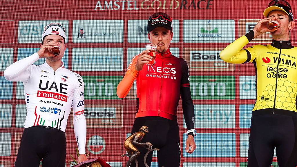 Marc Hirschi (links), Sieger Tom Pidcock und der drittplatzierte Belgier Tiesj Benoot gönnen sich auf dem Podium einen Schluck Bier