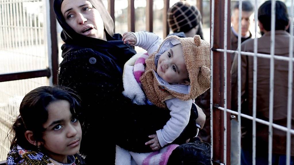 Eine syrische Mutter wartet mit ihren Kindern an der Grenze zur Türkei.