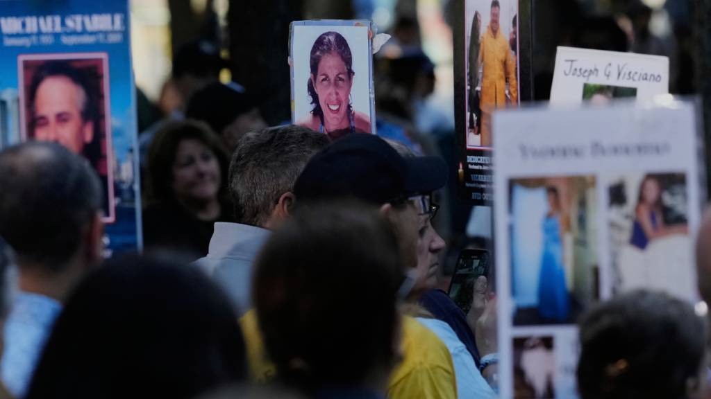 Menschen halten Bilder von Familienmitgliedern während einer Zeremonie zum 24. Jahrestag der Anschläge vom 11. September 2025 in New York hoch. Foto: Seth Wenig/AP/dpa