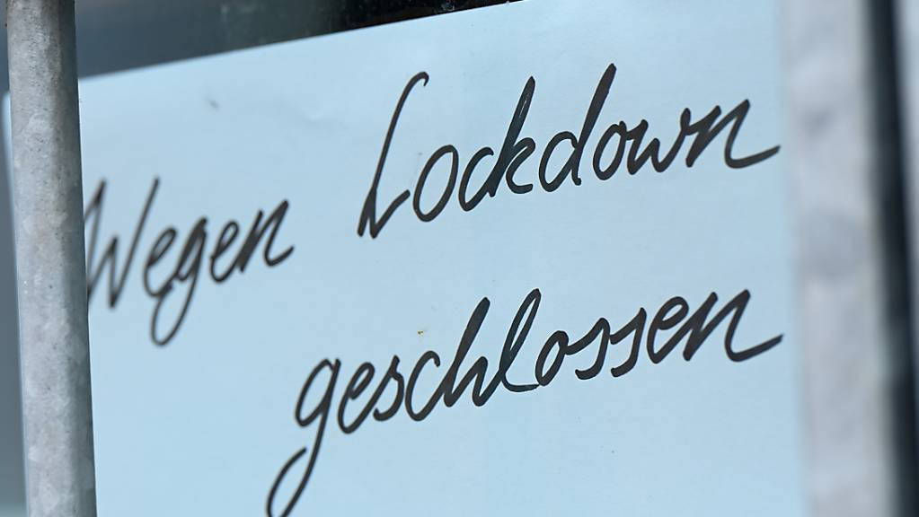 Ein Zettel mit der Aufschrift «Wegen Corona geschlossen» hängt am Schaufenster eines Geschäfts.