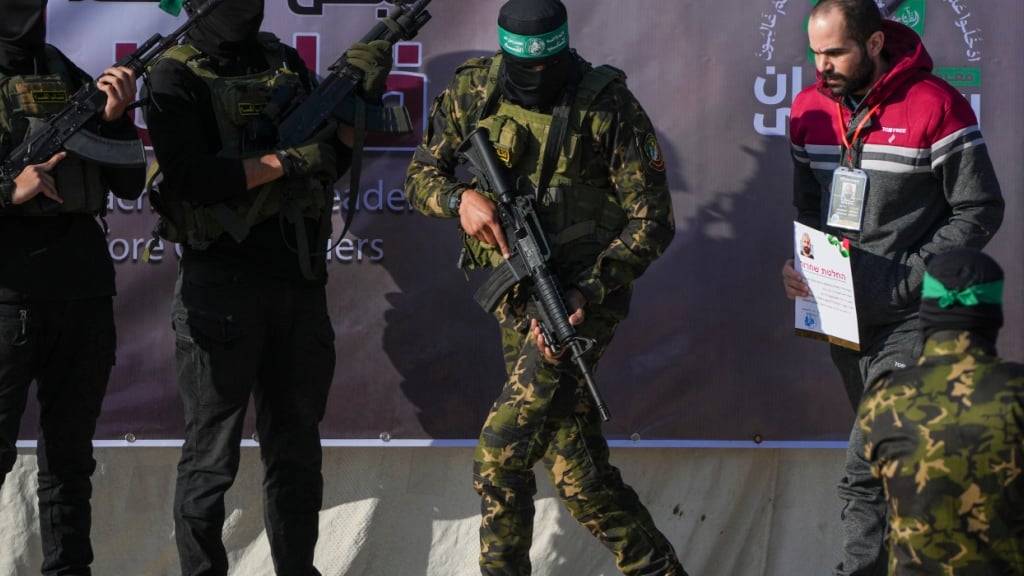 ARCHIV - Der Israeli Jarden Bibas wird von Hamas-Kämpfern eskortiert, bevor er dem Roten Kreuz übergeben wird. Foto: Abdel Kareem Hana/AP/dpa/Archivbild
