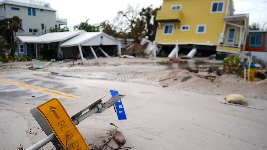 Ein Haus ist nach dem Durchzug des Hurrikans «Milton» von seinen Stelzen gestürzt und steht neben einem leeren Grundstück, auf dem ein Haus von Hurrikan «Helene» weggefegt wurde auf Anna Maria Island. Foto: Rebecca Blackwell/AP/dpa