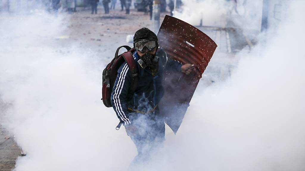 Ein Anti-Regierungs-Protestler läuft durch Wolken von Tränengas während Zusammenstössen mit der Polizei. Kolumbianer sind seit Wochen im ganzen Land auf die Straße gegangen.In der Stadt Cali waren am Freitag und in der Nacht zum Samstag Medien zufolge mindestens sechs Menschen im Zusammenhang mit den Demonstrationen ums Leben gekommen.
