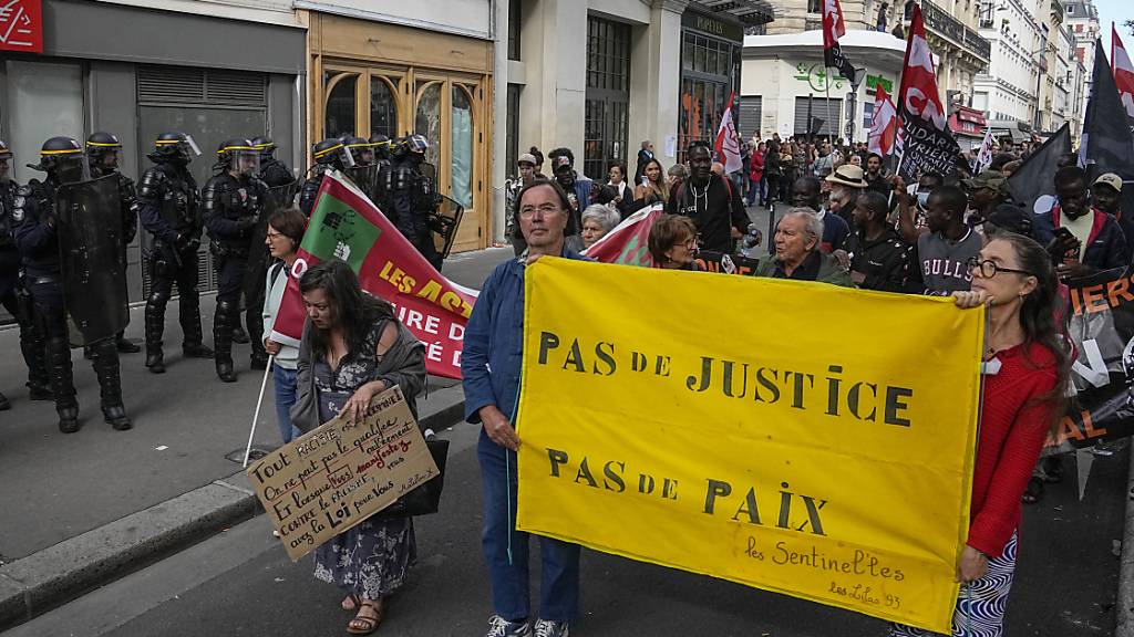 Menschen demonstrieren mit einem Transparent mit der Aufschrift «Keine Gerechtigkeit, kein Frieden» in Paris. Foto: Michel Euler/AP/dpa