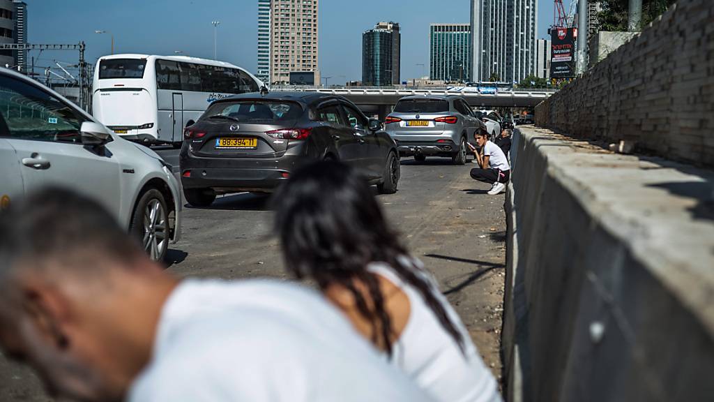 Menschen suchen am Rand einer Straße Schutz während eine Sirene ertönt, während die Kämpfe zwischen der militanten palästinensischen Gruppe Hamas und Israel weitergehen. Foto: Ilia Yefimovich/dpa