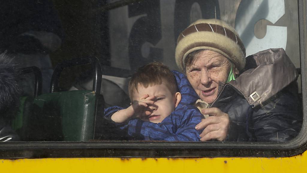  Eine ältere Frau und ein Junge schauen durch das Fenster eines Busses und warten auf ihre Evakuierung nach Russland. Foto: Alexei Alexandrov/AP/dpa