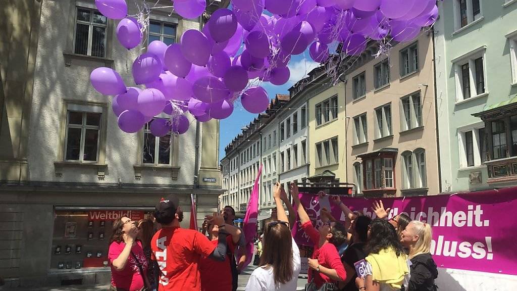 Frauen fordern Lohngleichheit und lassen lila Ballone in den St. Galler Himmel steigen.