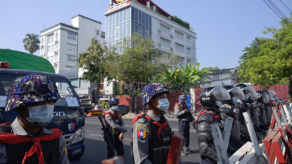 Polizisten sperren eine Straße in Rangun. Zahlreiche Menschen demonstrieren gegen den Militärputsch. Foto: Thet Htoo/ZUMA Wire/dpa