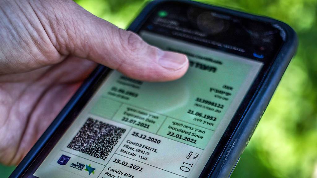 Ein Mann hält ein Smartphone in der Hand, auf dem der sogenannte «Grüne Pass» abgebildet ist. Wegen steigender Corona-Infektionszahlen gilt in Israel seit Donnerstag wieder der sogenannte Grüne Pass.