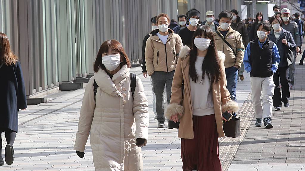 Passanten tragen Schutzmasken und gehen einen Bürgersteig in Tokio entlang. Foto: Koji Sasahara/AP/dpa