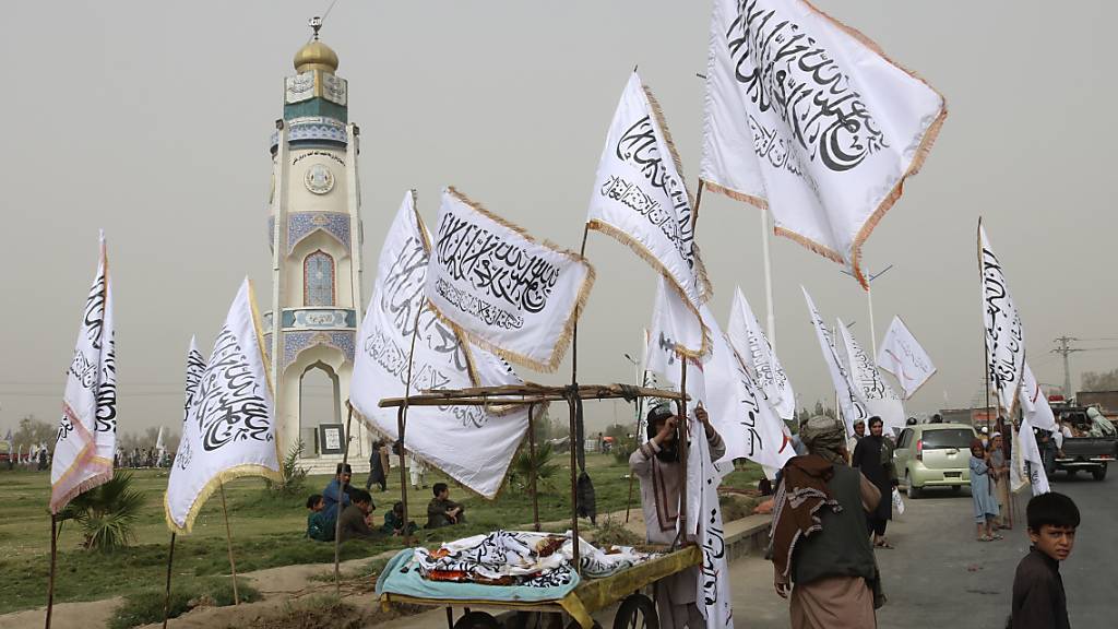 dpatopbilder - Ein afghanischer Mann und Kinder verkaufen während einer Feier zum zweiten Jahrestag des Abzugs der US-amerikanischen Truppen aus Afghanistan Taliban-Fahnen an Passanten. Foto: Abdul Khaliq/AP/dpa