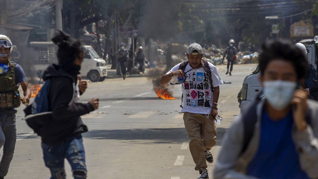 Demonstrantenlaufen vor der Polizeidavon. Seit Beginn der Proteste gegen den Militärputsch in Myanmar sind bei den brutalen Auseinandersetzungen viele zu Tode gekommen. Foto: Uncredited/AP/dpa