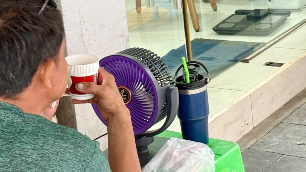 Ein Mann erfrischt sich bei Hitze an einem  Ventilator. Foto: Carola Frentzen/dpa