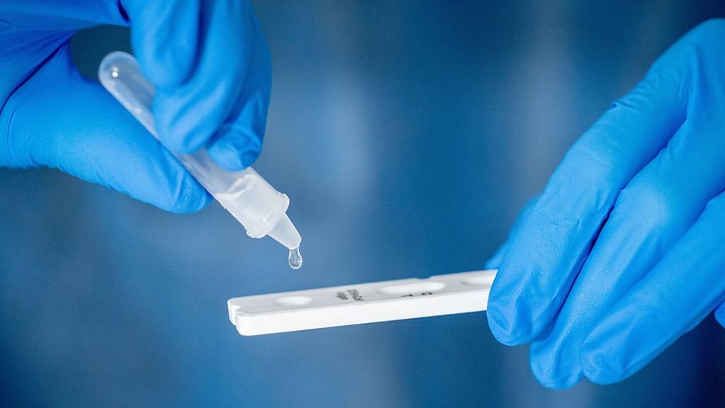 ARCHIV - Medizinisch geschultes Personal träufelt nach dem Abstrich für einen Corona-Schnelltest in eine Lösung auf die Antigen Testkasette. Foto: Kay Nietfeld/dpa