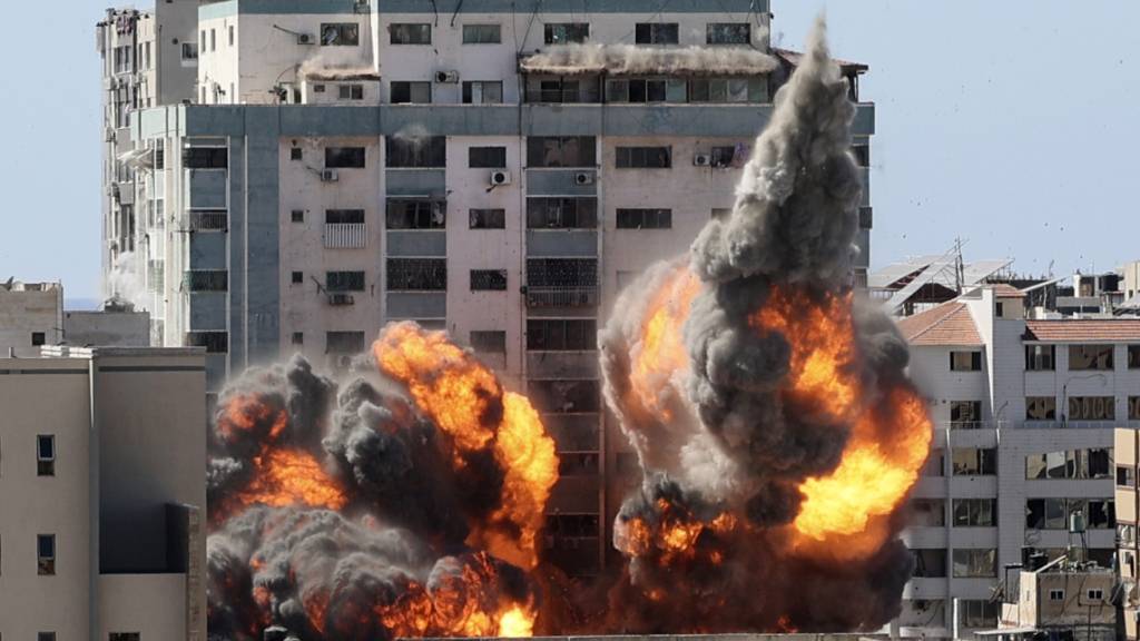 dpatopbilder - Rauch und Feuer steigen aus einem Gebäude nach einem israelischen Luftangriff auf. In dem Gebäude sind verschiedene internationale Medien untergebracht, darunter auch die Associated Press und Al-Dschasira. Foto: Mahmud Hams/POOL AFP/AP/dpa