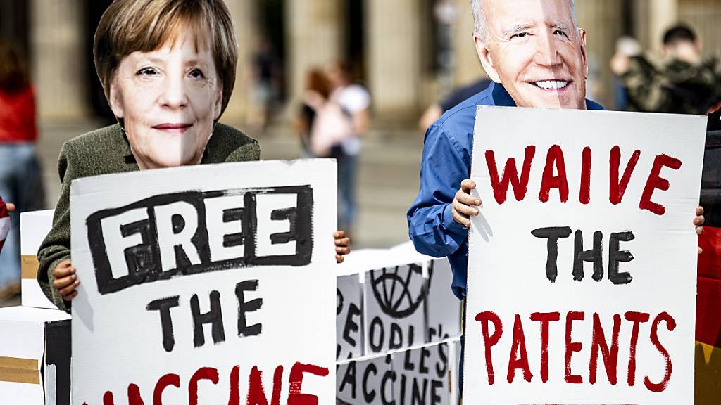 Aktivisten mit Masken, die Bundeskanzlerin Merkel und den US-Präsidenten Biden darstellen, stehen vor dem Brandenburger Tor in Berlin. Die Aktivisten fordern die vorübergehende Aussetzung des Patentschutzes für die Covid-Impfstoffe. Foto: Fabian Sommer/dpa