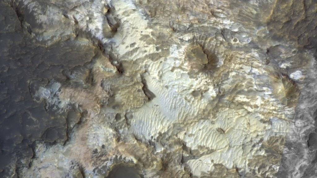 Eingefärbtes Bild des Bodens des Kibuye-Kraters in der
Region Terra Sirenum. Die Tönungen zeugen von der
reichen Vielfalt der mineralogischen Zusammensetzung
dieser Felsen. Chloridsalz und Tonmineralien wurden
hier aus dem Orbit mit Infrarotspektrometern identifiziert.