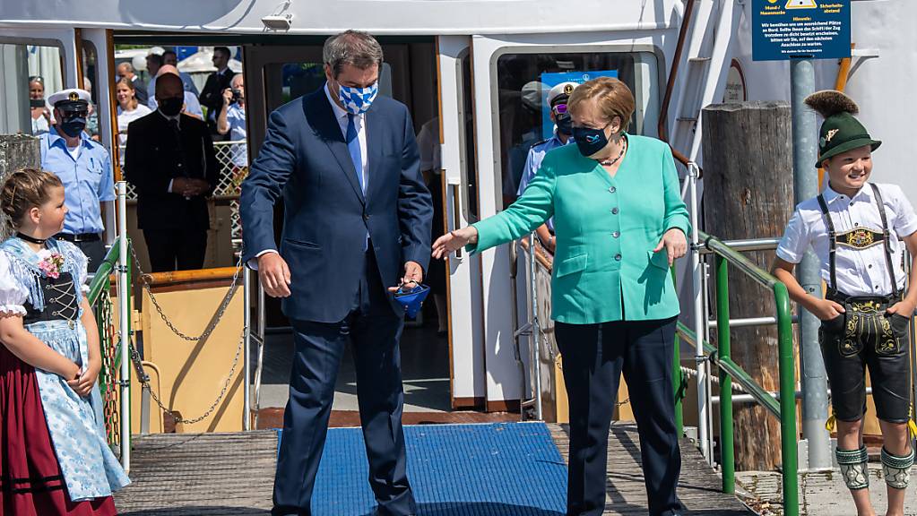 Markus Söder (CSU), Ministerpräsident von Bayern, empfängt an der Schiffsanlegestelle Prien Bundeskanzlerin Angela Merkel (CDU), um anschließend mit einem Schiff der Chiemsee-Schifffahrt auf die Insel Herrenchiemsee überzusetzen. Foto: Peter Kneffel/dpa/Pool/dpa