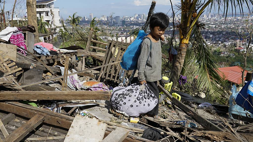 Romel Lo-ang holt persönliche Gegenstände aus ihrem beschädigten Haus. «Rai», der bisher stärkste Taifun dieses Jahres auf den Philippinen, hat bei seinem Durchzug zwischen Donnerstag und Samstag mindestens 142 Tote gefordert und eine Spur der Verwüstung hinterlassen. Foto: Jay Labra/AP/dpa