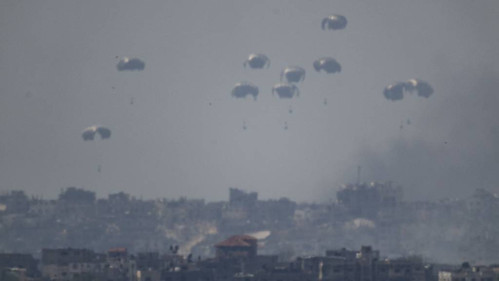 Fallschirme werfen Versorgungsgüter in den nördlichen Gazastreifen ab, vom Süden Israels aus gesehen. Foto: Leo Correa/AP/dpa