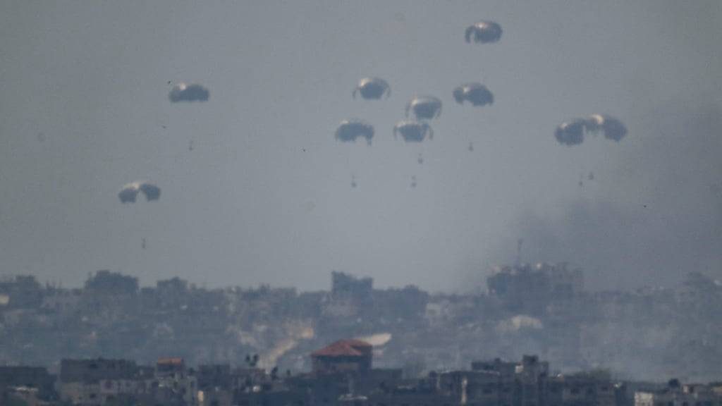 Fallschirme werfen Versorgungsgüter in den nördlichen Gazastreifen ab, vom Süden Israels aus gesehen. Foto: Leo Correa/AP/dpa