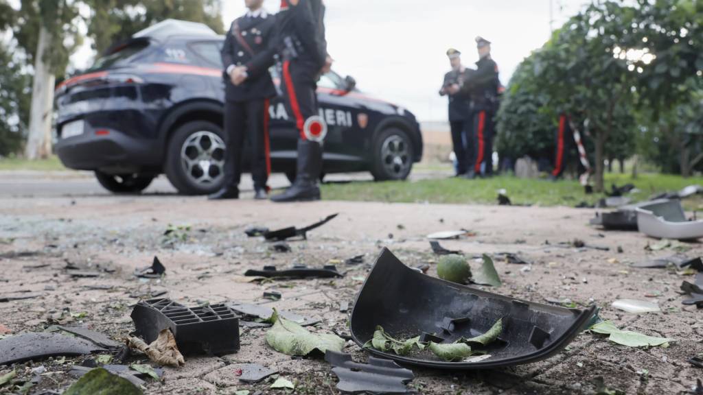 Autoteile liegen nach einem Sprengstoffanschlag auf dem Boden, während Carabinieri der Militärpolizei in dem Vorort Roms vor dem Haus des Investigativ-Reporter Sigfrido Ranucci stehen. Die Hintergründe sind unklar. Verletzt wurde niemand. Foto: Cecilia Fabiano/LaPresse via AP/dpa - ACHTUNG: Nur zur redaktionellen Verwendung und nur mit vollständiger Nennung des vorstehenden Credits