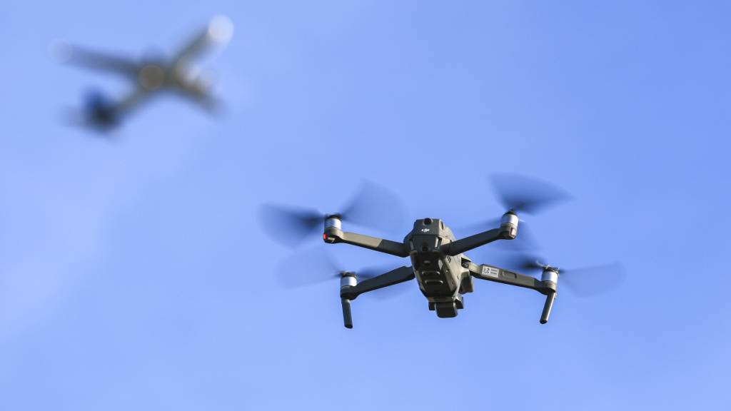 ARCHIV - Eine Drohne fliegt vor einem startenden Flugzeug in der Nähe des Flughafens Leipzig/Halle. Foto: Jan Woitas/dpa