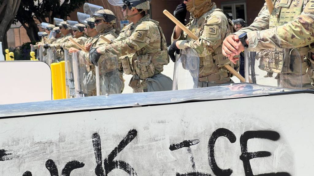 ARCHIV - Soldaten der kalifornischen Nationalgarde stehen hinter einer Absperrung, auf die «Fuck ICE» aufgesprüht wurde. Foto: Benno Schwinghammer/dpa/Archivbild