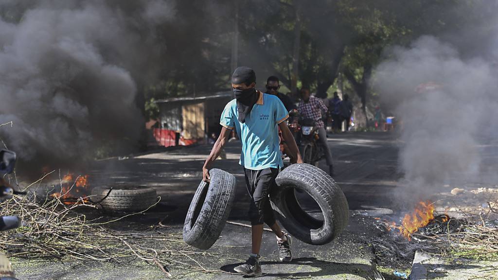 Ein Anwohner trägt Reifen zu einer brennenden Barrikade, die Bandenmitglieder abhalten soll, in sein Viertel in Port-au-Prince, Haiti, einzudringen.