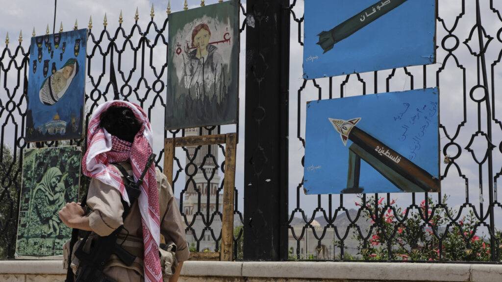 Ein jemenitischer Bewaffneter geht an Gemälden vorbei, auf denen Raketen und Szenen der Solidarität mit dem Gazastreifen abgebildet sind. Foto: Osamah Abdulrahman/AP/dpa