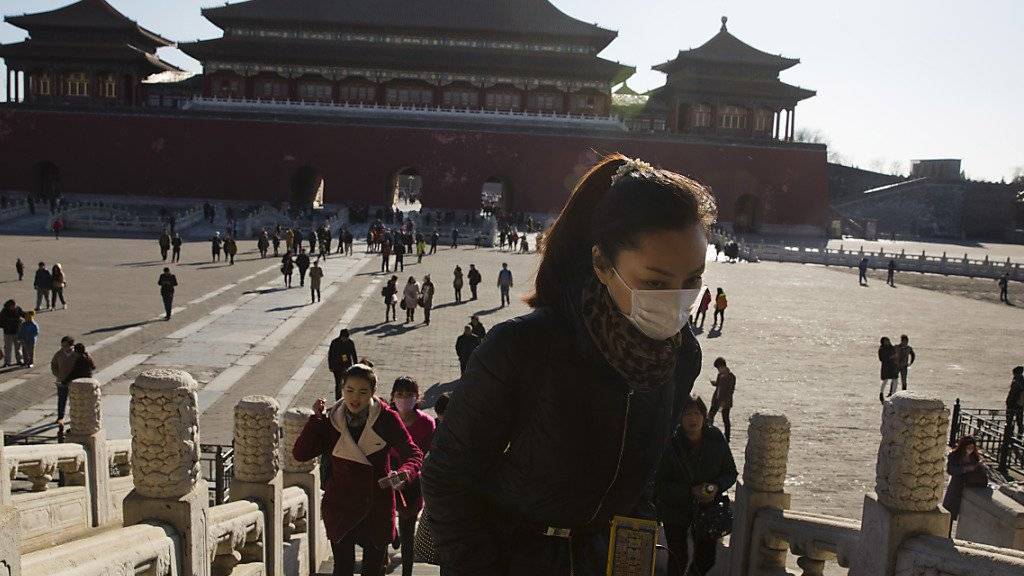 Smog-Alarm in Peking trotz sonnigem Wetter: Eine Frau schützt sich in der Verbotenen Stadt mit einer Maske. Die höchste Smog-Alarmstufe gilt bis Dienstag.