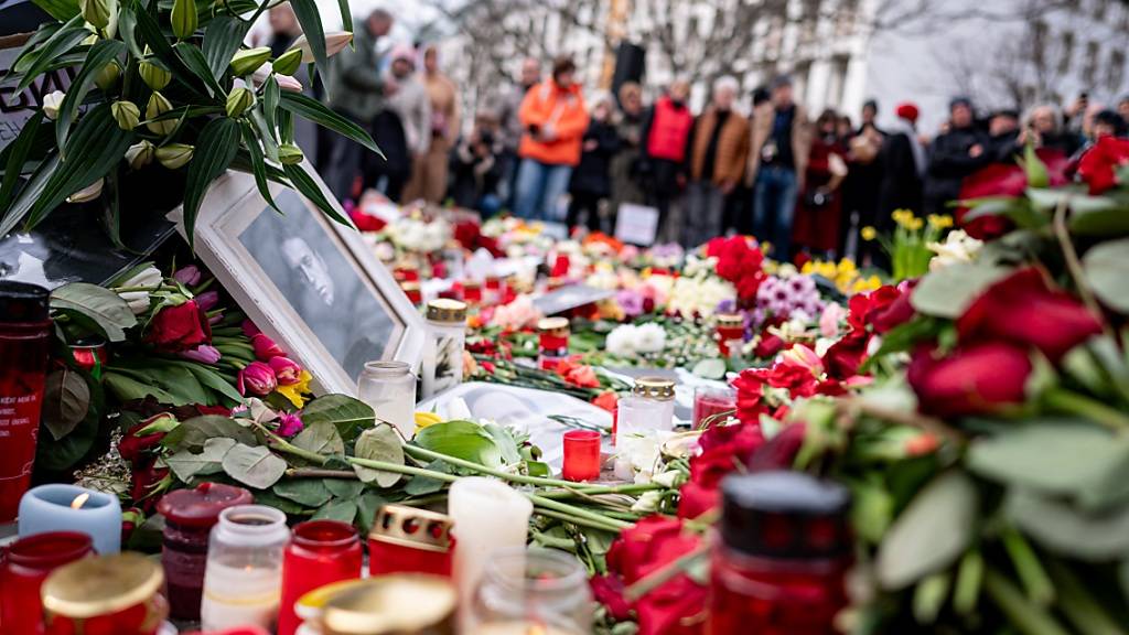 Menschen stehen nach dem Tod des Regimekritikers Nawalny an einer Demonstration gegen die russische Regierung vor der russischen Botschaft in Berlin-Mitte vor Blumen. Foto: Fabian Sommer/dpa