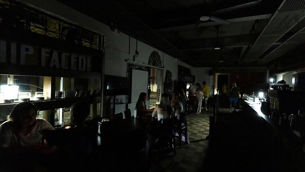 Kunden sitzen in einem Restaurant, das während eines inselweiten Stromausfalls mit batteriebetriebenen Laternen beleuchtet wird. Foto: Alejandro Granadillo/AP/dpa