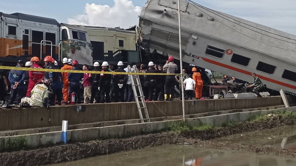 Rettungskräfte inspizieren die Trümmer von Zügen nach einem Zusammenstoß. Foto: Abdan Syakura/AP/dpa