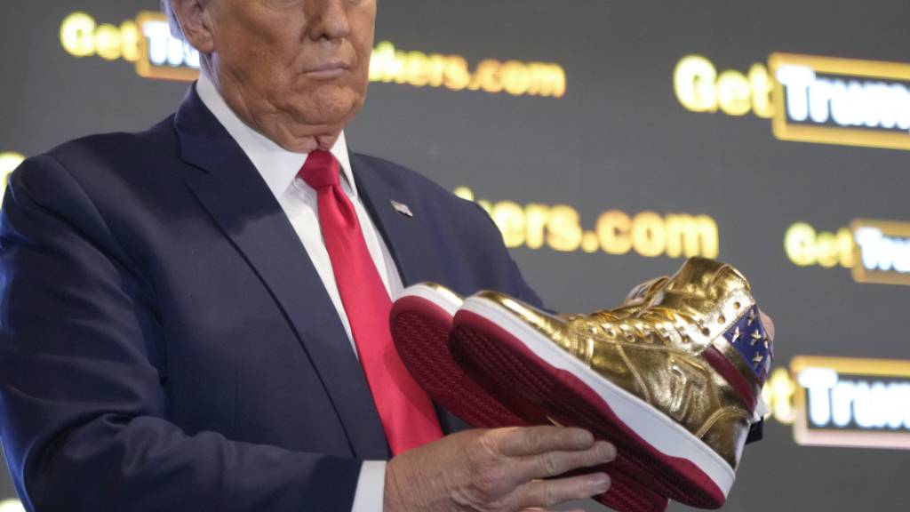 dpatopbilder - Der republikanische Präsidentschaftskandidat und ehemalige Präsident Donald Trump hält goldene Trump-Sneakers auf der Sneaker Con Philadelphia, einer Veranstaltung für Sneakersammler, in Händen. Foto: Manuel Balce Ceneta/AP/dpa