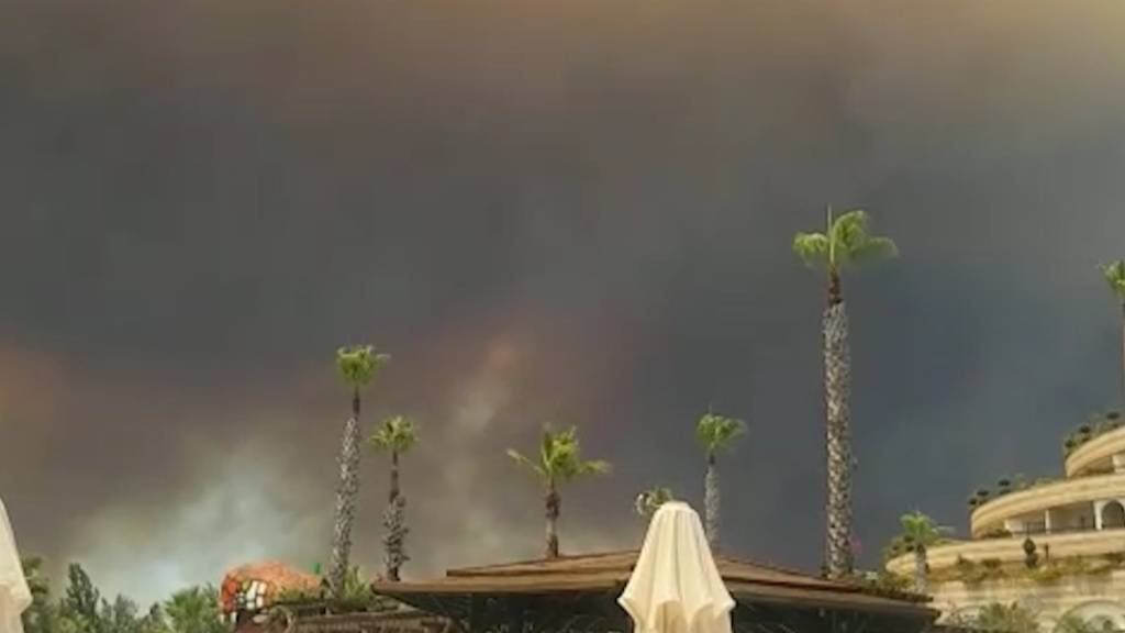 Dunkler Rauch zieht über einen Hotelkompex in der türkischen Urlaubsregion Antalya hinweg. Winde trieben die Flammen mehrerer Waldbrände in Richtung der Wohnbezirke, wie der Landrat des Bezirks Manavgat dem Sender CNN Türk sagte. Foto: Cevin Dettlaff/dpa-Zentralbild/dpa