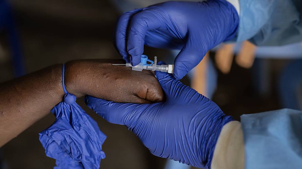 ARCHIV - Ein Mitarbeiter des Gesundheitswesens kümmert sich um einen Mpox-Patienten in einem Behandlungszentrum. Foto: Moses Sawasawa/AP/dpa