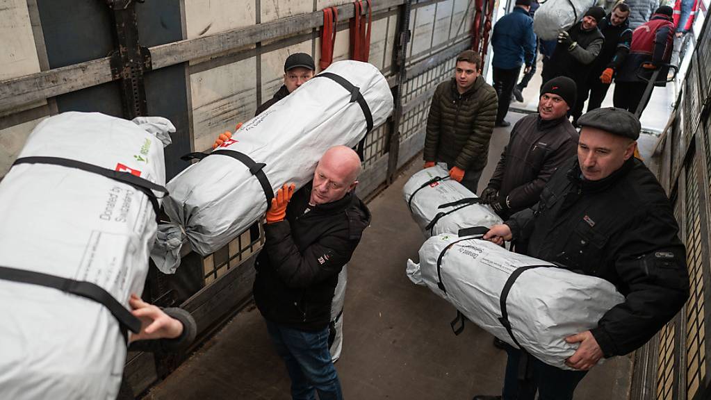 Mitglieder des Schweizerisches Korps für Humanitäre Hilfe (SKH) und Caritas Ukraine laden Schweizer Hilfsgüter beim polnisch-ukrainischen Grenzübergang Hrebenne/Rawa-Ruska auf ukrainische Lastwagen um. (Aufnahme vom 3. März 2022)
