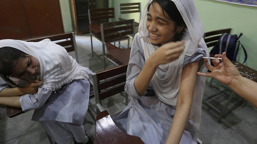 Eine Schülerin wirde in einer Schule mit einer Dosis des Corona-Impfstoffs von Pfizer geimpft. In Pakistan sind seit Beginn der Impfkampagne im Februar 100 Millionen Corona-Impfdosen verabreicht worden. Dies teilte das Gesundheitsministerium am Samstag mit. Foto: K.M. Chaudary/AP/dpa